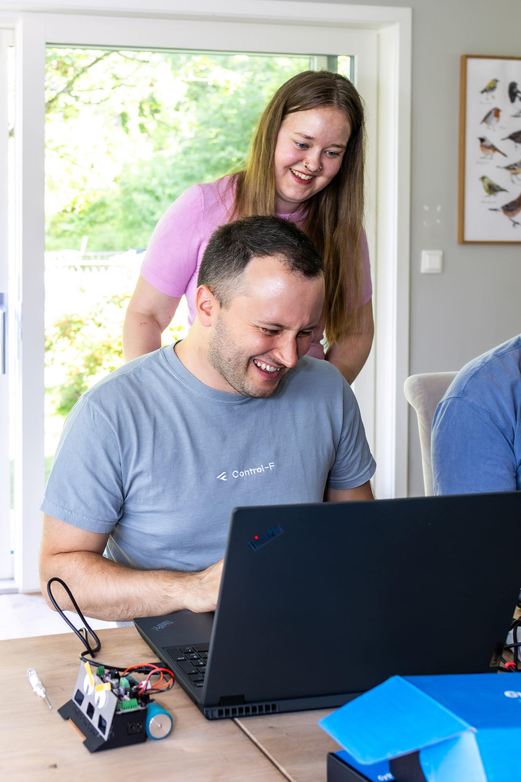 Eine Kollegin und ein Kollege schauen gemeinsam lachend auf einen Laptop-Bildschirm
